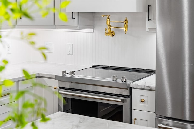 kitchen featuring light stone counters, appliances with stainless steel finishes, and white cabinetry