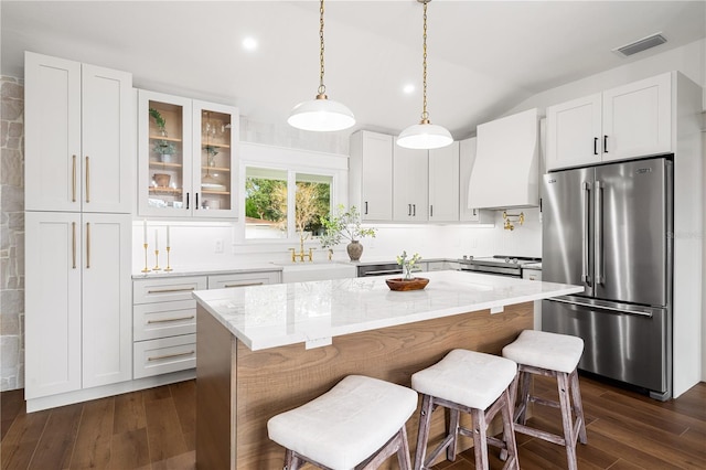 kitchen featuring custom exhaust hood, a kitchen island, white cabinetry, appliances with stainless steel finishes, and sink