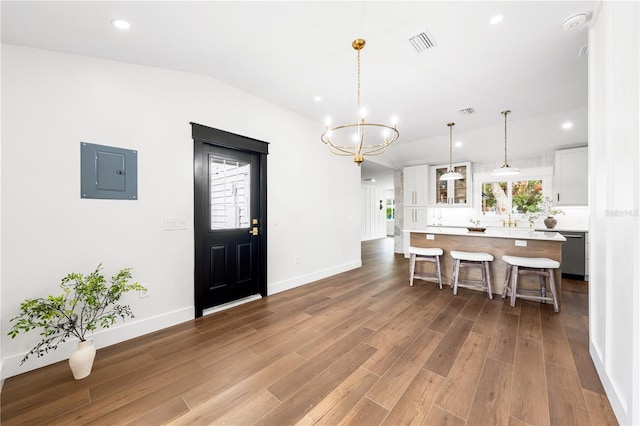 kitchen featuring pendant lighting, electric panel, a kitchen island, a breakfast bar area, and white cabinetry