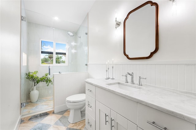 bathroom featuring a shower with shower door, vanity, and toilet