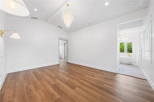 empty room with a chandelier, hardwood / wood-style floors, vaulted ceiling with beams, and wood ceiling