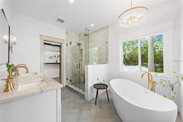 bathroom featuring a notable chandelier, separate shower and tub, and vanity