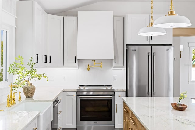 kitchen featuring stainless steel appliances, light stone countertops, white cabinets, decorative light fixtures, and sink