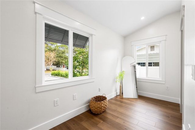 unfurnished room featuring vaulted ceiling, hardwood / wood-style floors, and a healthy amount of sunlight