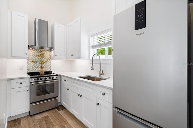 kitchen featuring white cabinets, stainless steel appliances, sink, wall chimney range hood, and backsplash