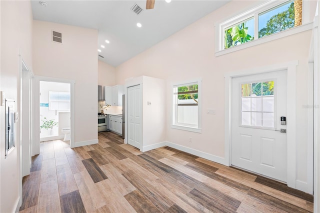 entryway with light hardwood / wood-style floors and high vaulted ceiling