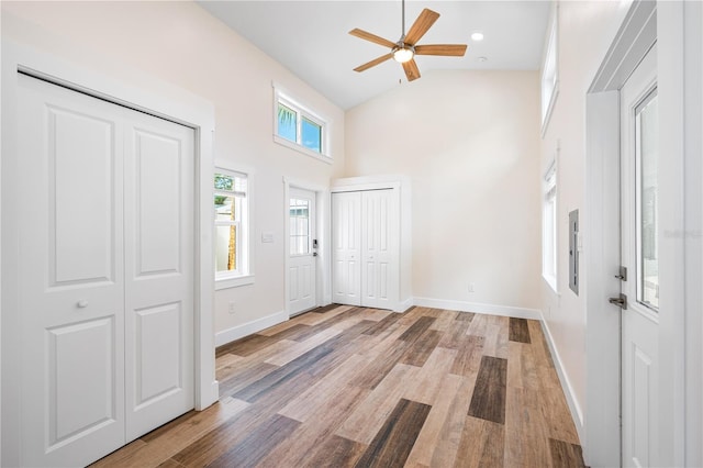 foyer entrance with light hardwood / wood-style floors, ceiling fan, and high vaulted ceiling