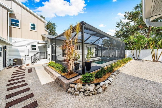 exterior space with a lanai, central air condition unit, and a fenced in pool