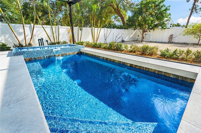 view of swimming pool featuring a fenced backyard and a pool with connected hot tub