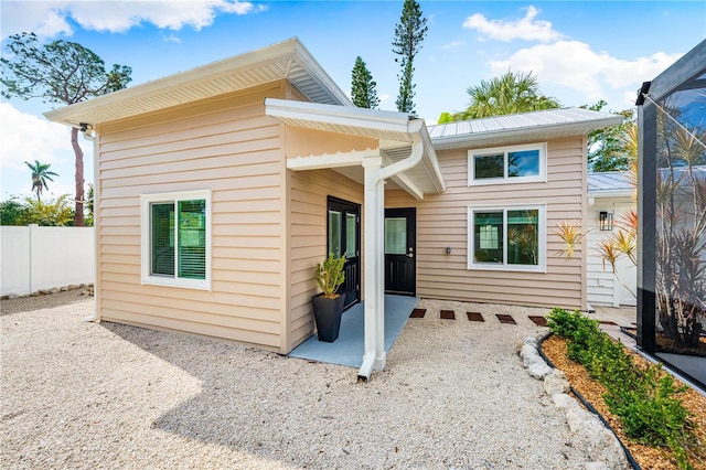 rear view of house with a lanai, fence, metal roof, and a patio