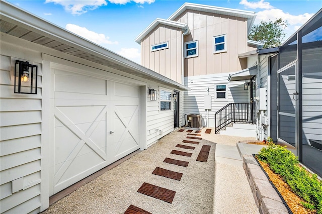 back of house featuring board and batten siding, cooling unit, and an attached garage