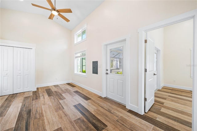 foyer entrance featuring high vaulted ceiling, wood finished floors, electric panel, and baseboards