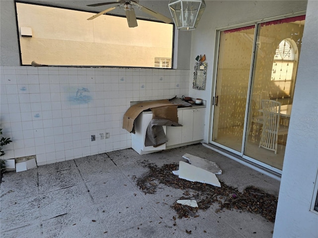 bathroom featuring ceiling fan and tile walls