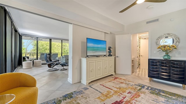 living room featuring ceiling fan and expansive windows