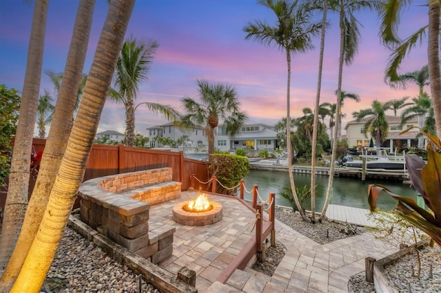 patio terrace at dusk featuring a water view and an outdoor fire pit