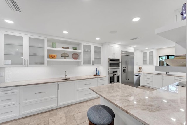 kitchen featuring white cabinets, sink, light stone counters, and stainless steel appliances