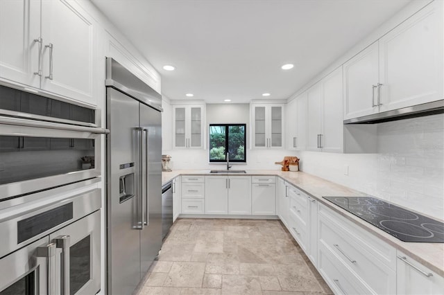 kitchen with light stone countertops, sink, tasteful backsplash, white cabinets, and appliances with stainless steel finishes