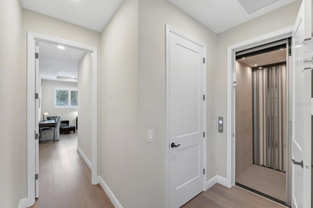 hall with light wood-type flooring and elevator