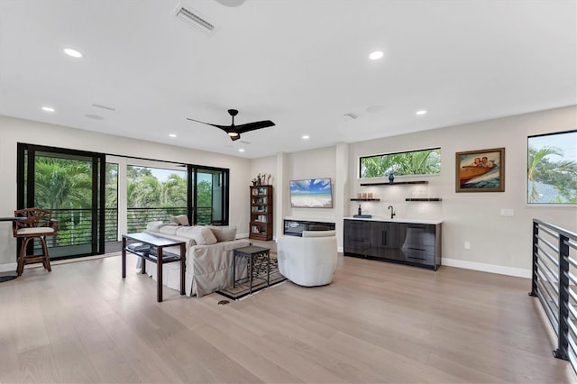 living room with ceiling fan and light hardwood / wood-style floors