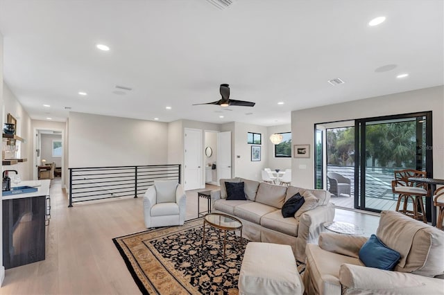 living room with light hardwood / wood-style flooring and ceiling fan