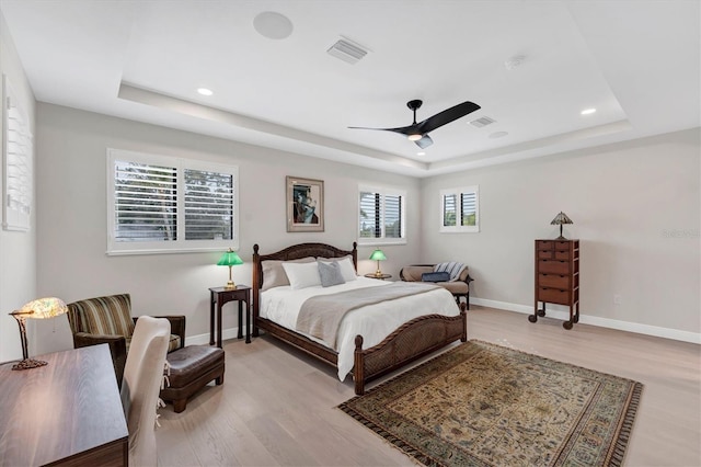 bedroom featuring ceiling fan, a raised ceiling, and light wood-type flooring