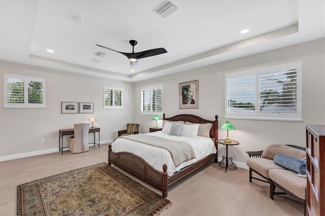 bedroom featuring ceiling fan, a raised ceiling, and multiple windows