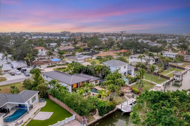 aerial view at dusk featuring a water view