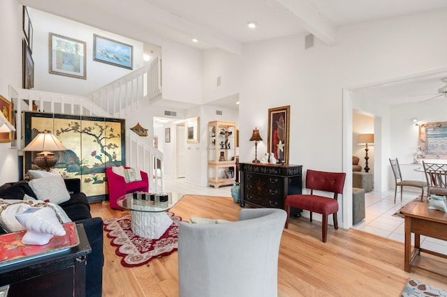 living room with hardwood / wood-style flooring, ceiling fan, a towering ceiling, and beam ceiling