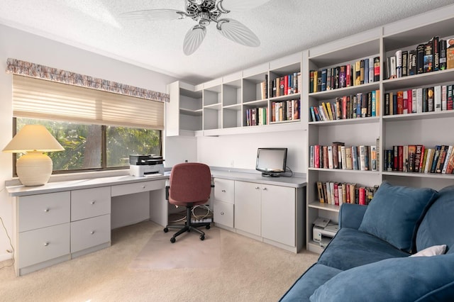 carpeted home office featuring ceiling fan, built in desk, and a textured ceiling