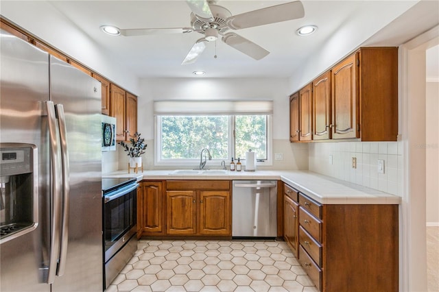 kitchen with decorative backsplash, ceiling fan, sink, and appliances with stainless steel finishes