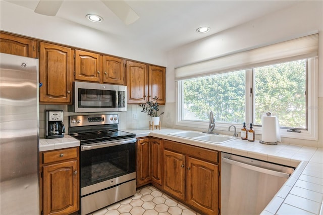 kitchen with sink, tile counters, backsplash, plenty of natural light, and appliances with stainless steel finishes