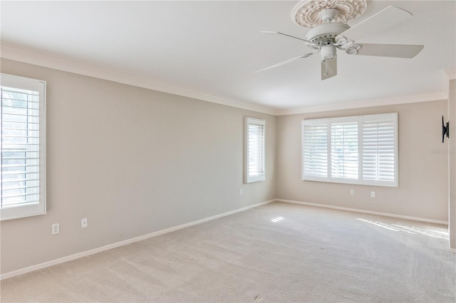 empty room featuring a wealth of natural light, crown molding, ceiling fan, and light carpet