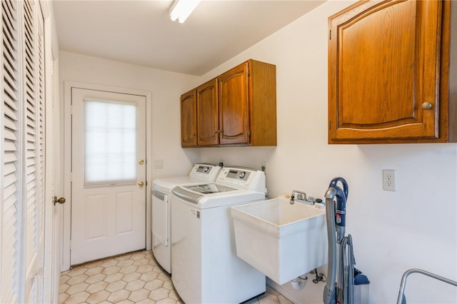 clothes washing area with washer and dryer, sink, and cabinets