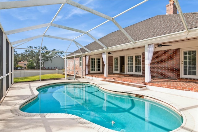 view of swimming pool featuring glass enclosure, ceiling fan, and a patio area