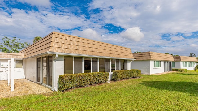 rear view of property featuring a lawn and a sunroom