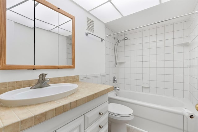 full bathroom featuring vanity, tiled shower / bath combo, and toilet