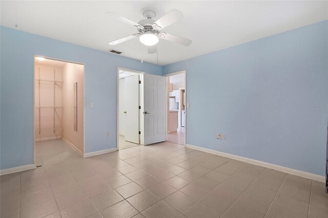 unfurnished bedroom with a spacious closet, a closet, and ceiling fan