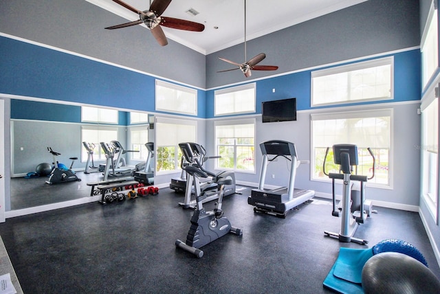 exercise room with ceiling fan, a towering ceiling, and ornamental molding