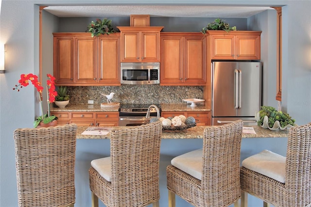 kitchen with decorative backsplash, sink, a breakfast bar area, and appliances with stainless steel finishes