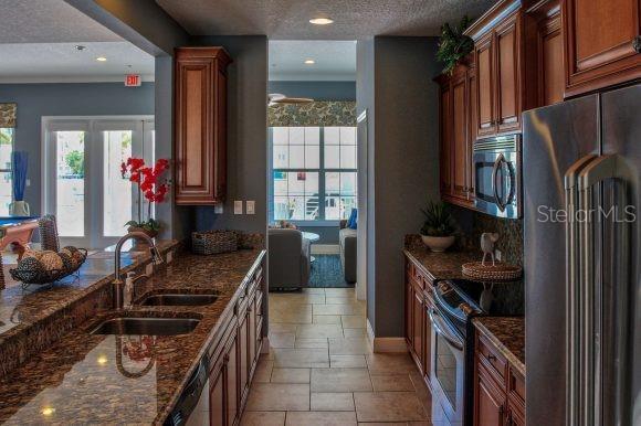 kitchen featuring appliances with stainless steel finishes, a textured ceiling, dark stone countertops, and sink