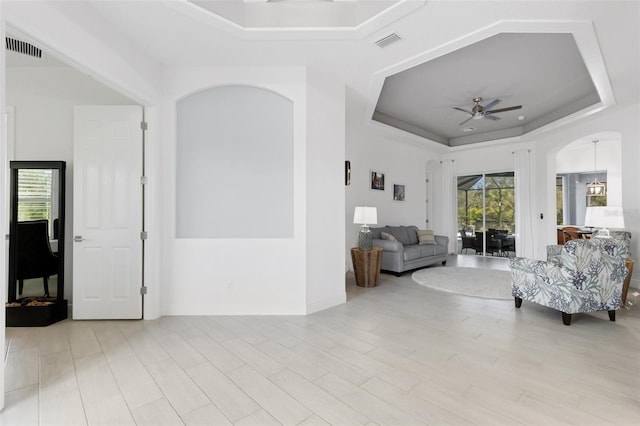 living room with a raised ceiling and ceiling fan