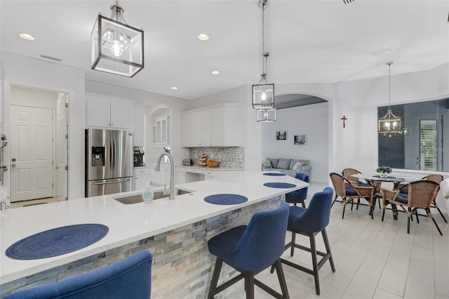 kitchen with tasteful backsplash, sink, decorative light fixtures, white cabinets, and stainless steel fridge with ice dispenser