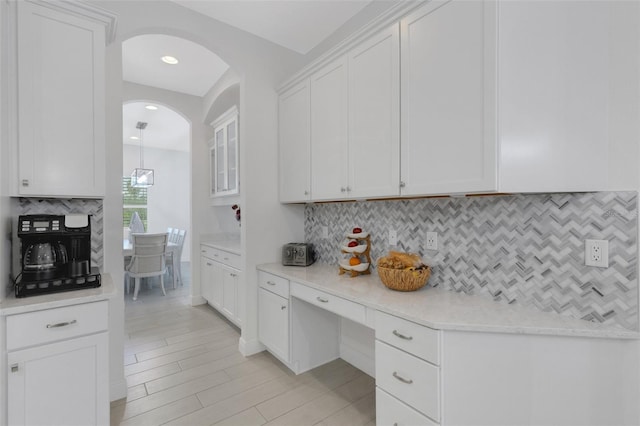 kitchen with backsplash, light stone countertops, and white cabinets