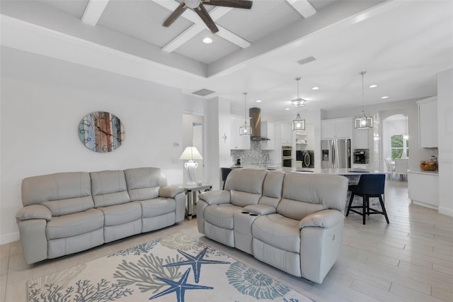 living room featuring beam ceiling, ceiling fan, and sink