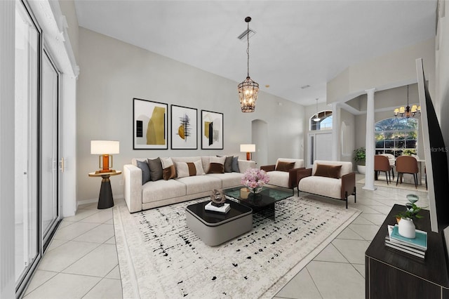 living room with decorative columns, light tile patterned floors, and an inviting chandelier