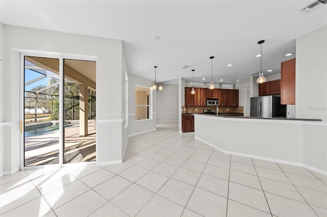 kitchen with appliances with stainless steel finishes, tasteful backsplash, light tile patterned floors, pendant lighting, and a chandelier