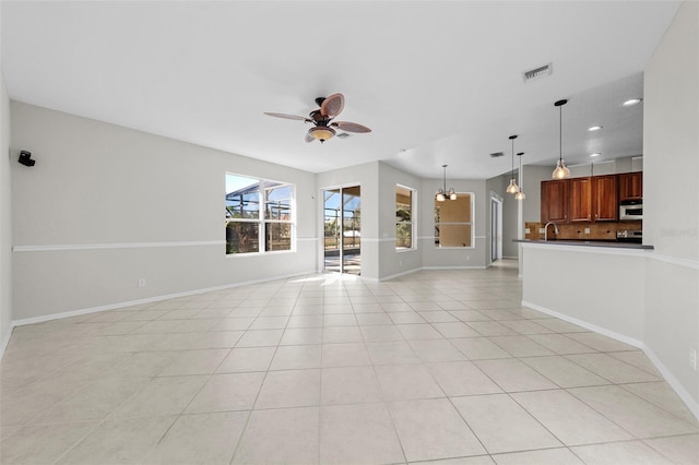 unfurnished living room featuring light tile patterned floors and ceiling fan with notable chandelier