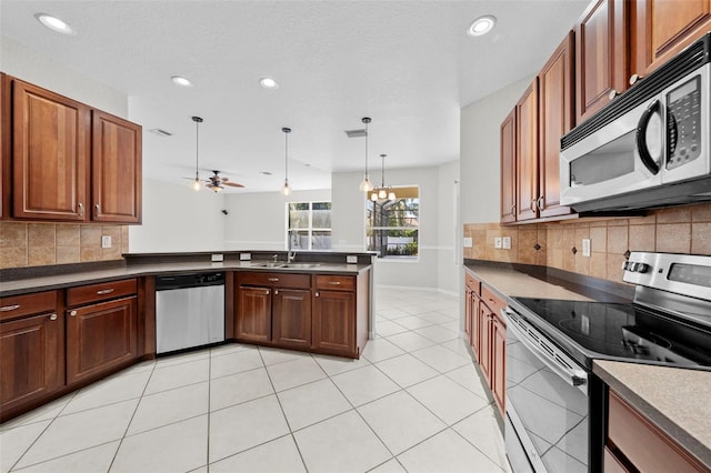 kitchen featuring backsplash, ceiling fan with notable chandelier, stainless steel appliances, and hanging light fixtures