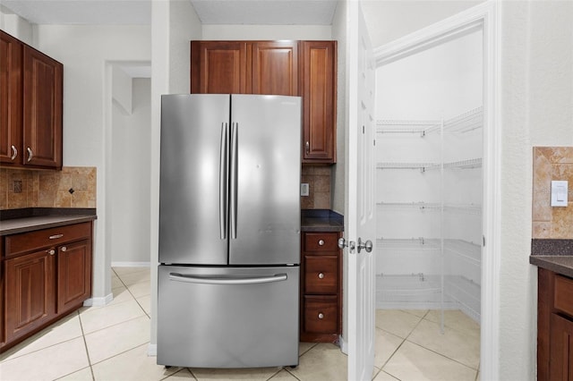 kitchen with light tile patterned floors, backsplash, and stainless steel refrigerator