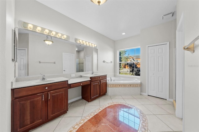 bathroom featuring tile patterned floors, a relaxing tiled tub, and vanity